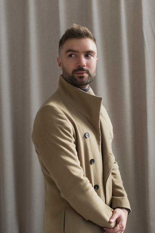 Man in Brown Coat Standing Near Brown Curtain