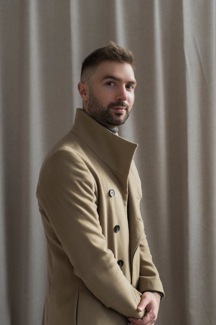 Man In Brown Coat Standing Near A Curtain