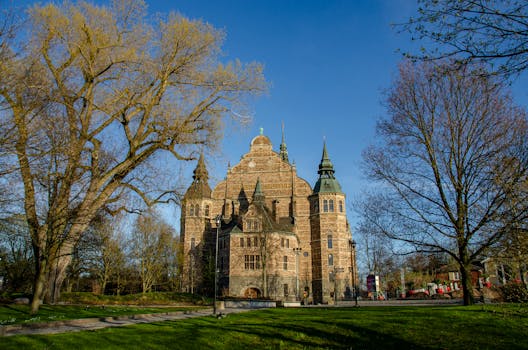 A scenic view of the Nordic Museum in Stockholm with trees under a clear blue sky.