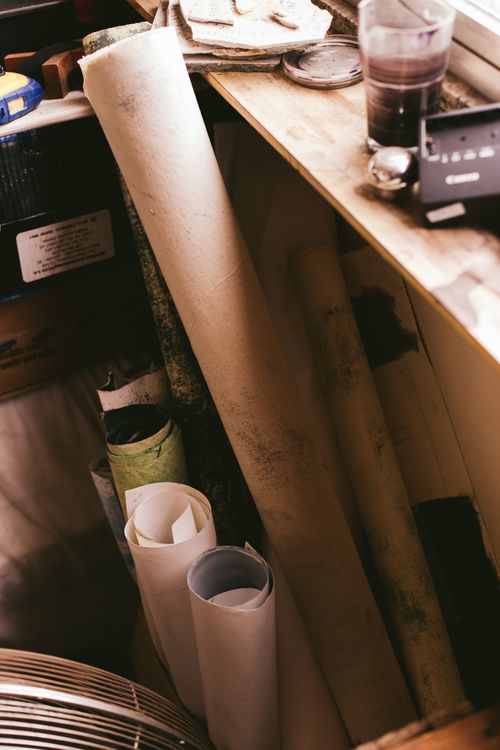 Free A cozy workspace featuring rolled blueprints and design materials on a wooden table. Stock Photo