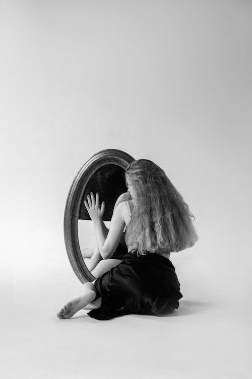 Woman Sitting with Hand on a Mirror