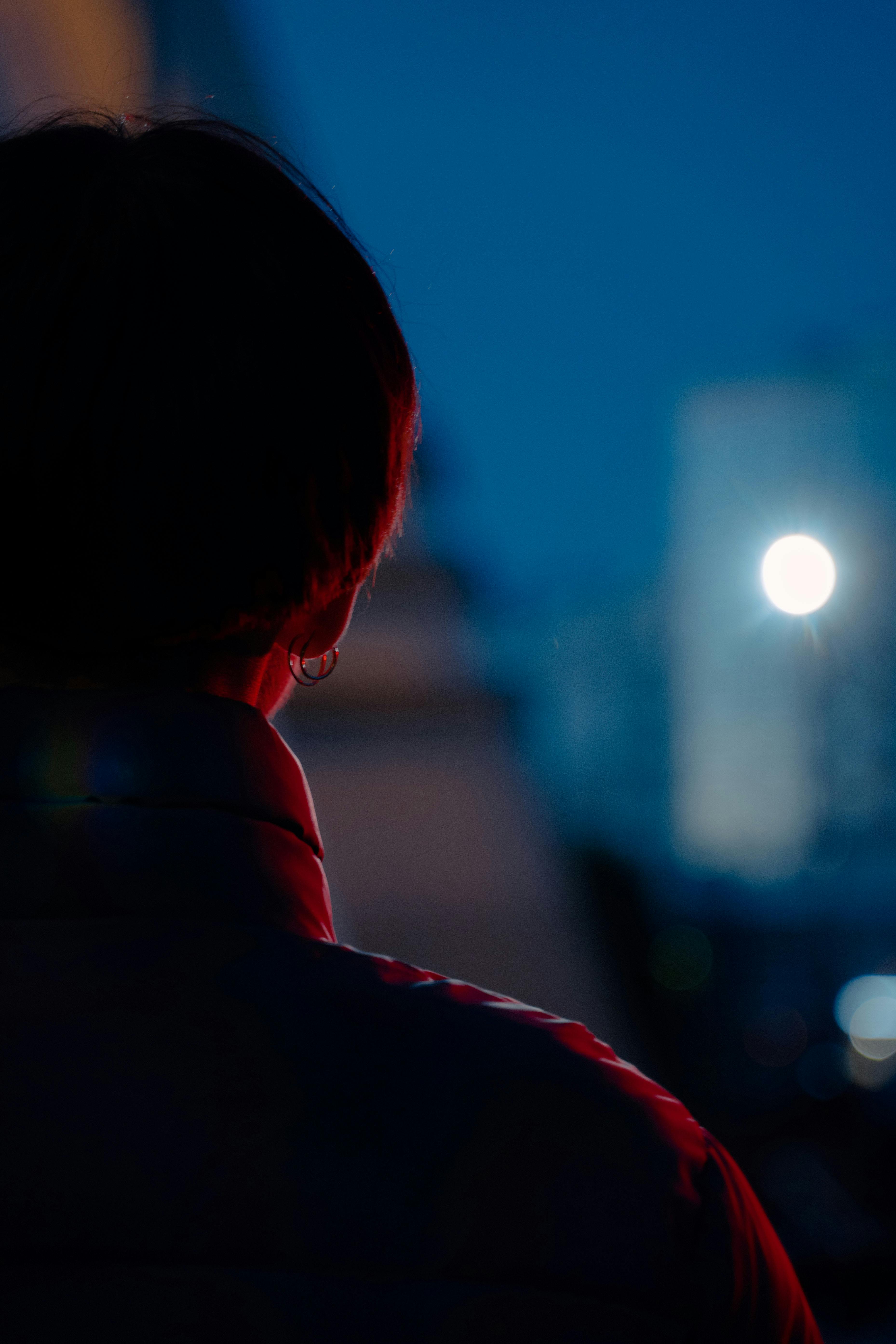 Person in puffer jacket gazing at city skyline during twilight