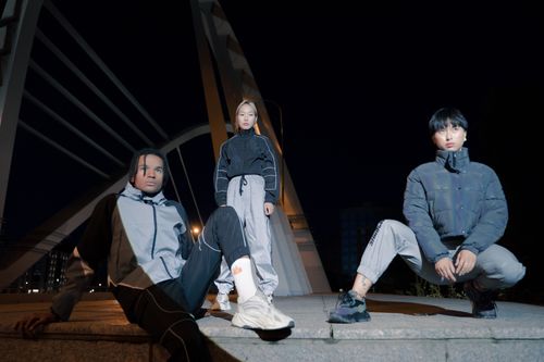 Free Stylish group in urban fashion poses on a modern bridge at night, exuding a trendy vibe. Stock Photo