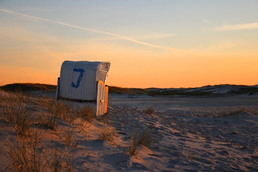 Peaceful sunset over a sandy beach on Amrum, featuring a classic wicker beach chair.
