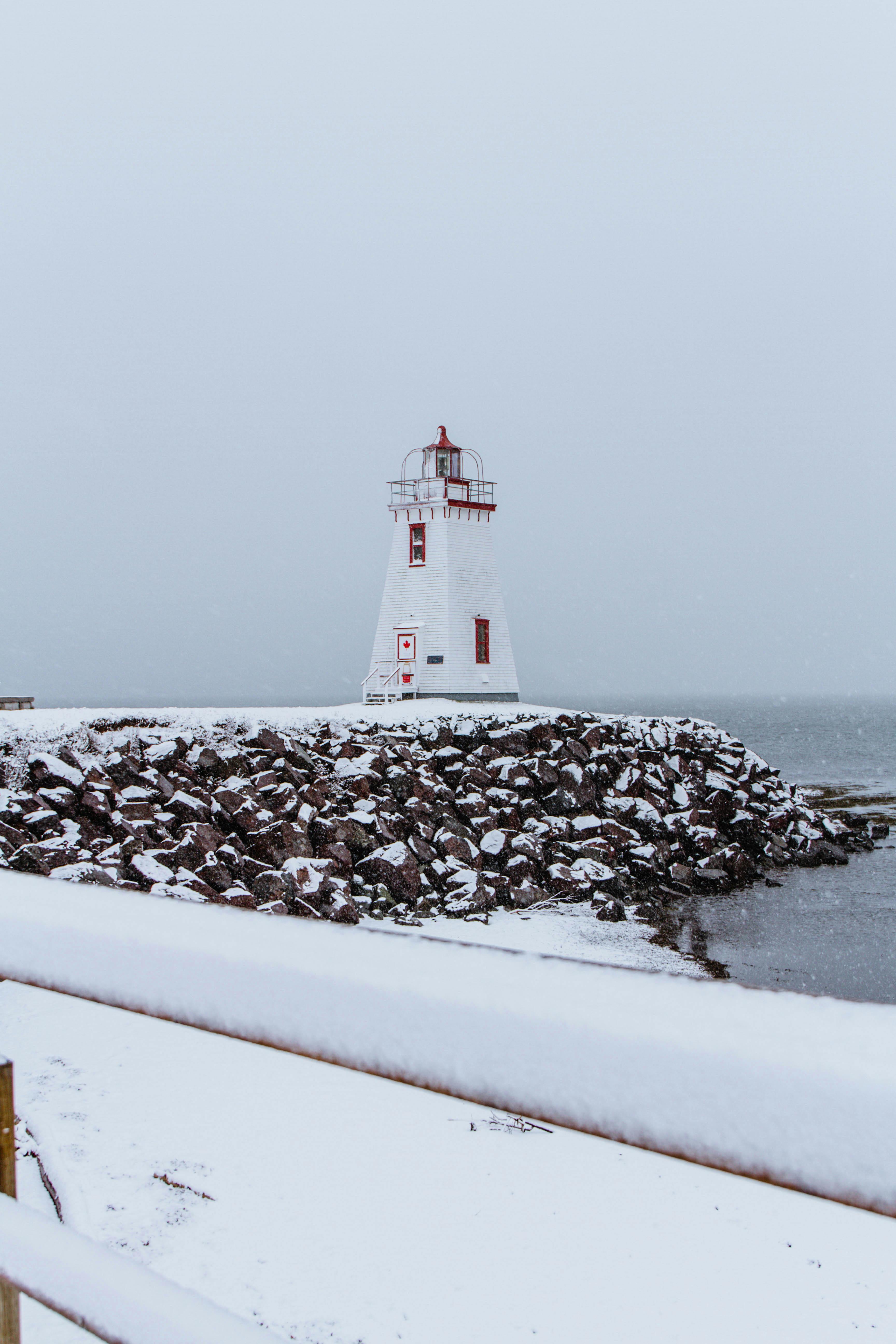 Free White and Red Lighthouse Near Body of Water Stock Photo