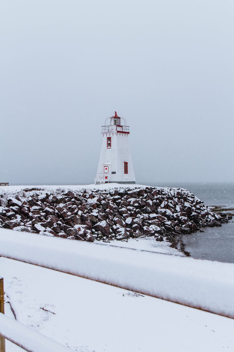 White And Red Lighthouse Near Body Of Water