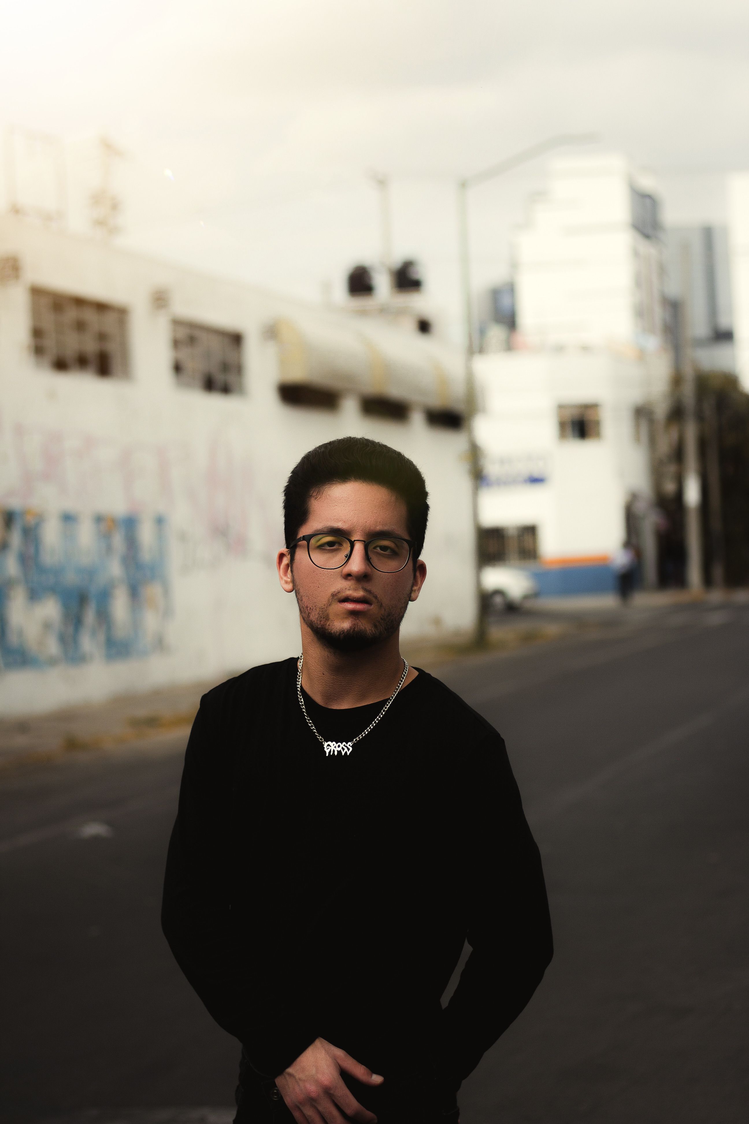 Stylish man poses confidently on an empty city street during the day.