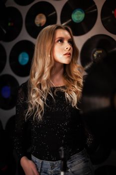 Stylish young woman looking up, surrounded by vintage vinyl records.
