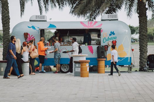 People gather at a colorful food truck, enjoying a lively outdoor setting.