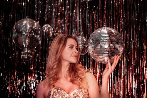 Free A woman in a sparkling dress celebrates with disco balls at a vibrant nightclub. Stock Photo