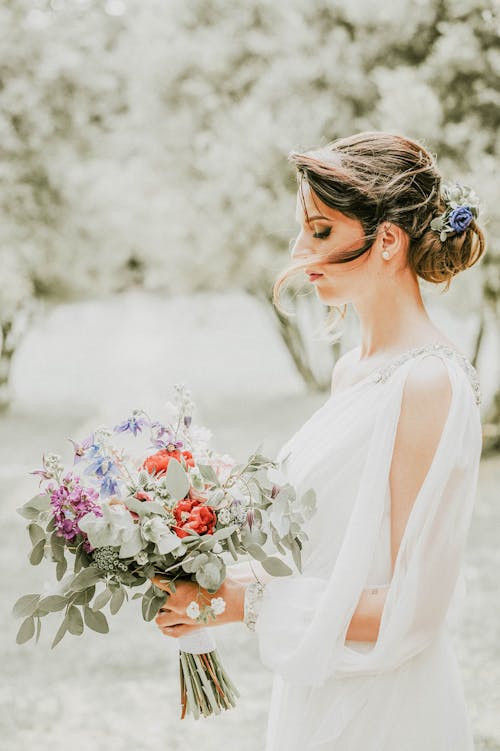 A Woman in White Dress Holding Bouquet of Flowers