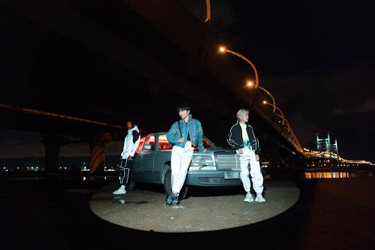 Models Standing By Car Under Bridge At Night