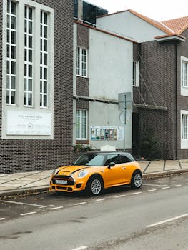 Yellow Mini Cooper parked on street in front of brick building in Kaliningrad, Russia. Urban transportation scene.