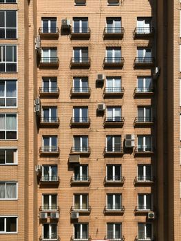 A modern building exterior showcasing windows, balconies, and air conditioning units.