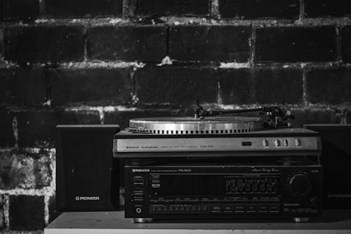 Grayscale Photo of a Turntable on Top of an Audio Receiver Beside a Speaker