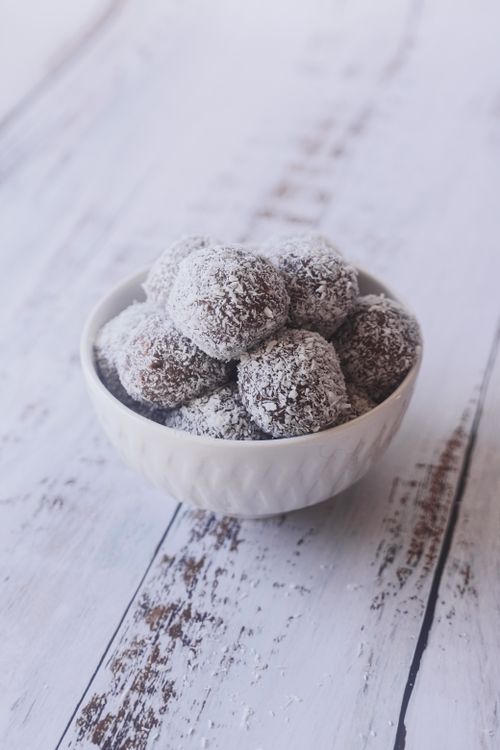 Free Bowl of chocolate dessert balls coated with grated coconut on a rustic wooden table. Stock Photo
