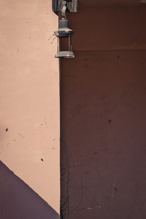 Free Artistic vertical shot of a vintage wall lamp mounted on a textured concrete wall, casting shadows. Stock Photo