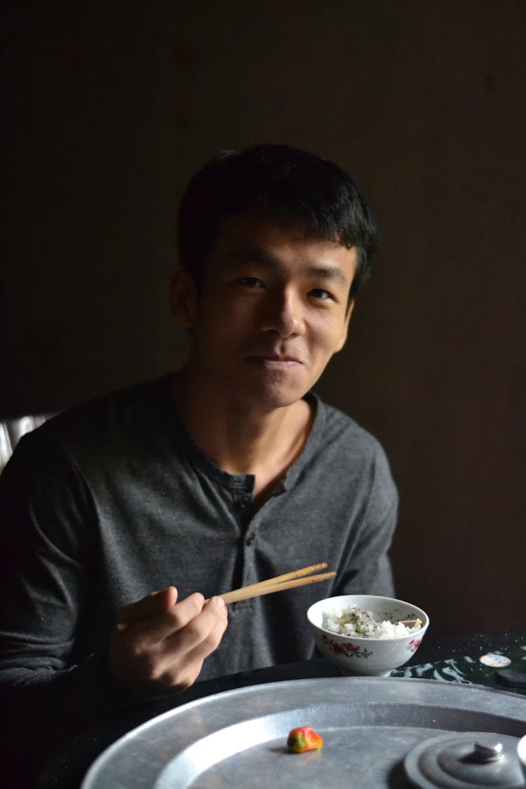 Man Eating Rice From A Bowl With Chopsticks