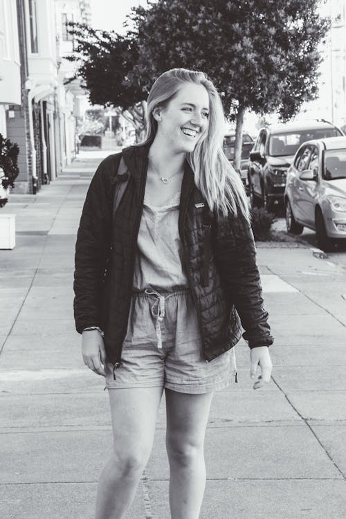 無料 通路に立っているジャケットを着ている笑顔の女性のグレースケール写真 写真素材