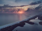 日落时分，从空中俯瞰宁静的沿海景观，水面倒映着天光