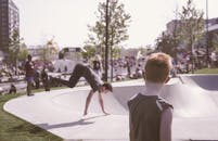 白天，人们在热闹的城市滑板公园观看特技表演