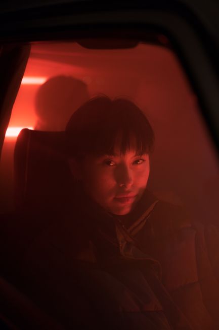 An atmospheric portrait of a person in red ambient light, creating a mysterious mood.