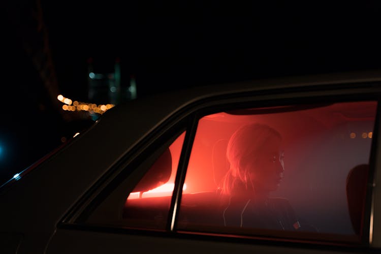 Woman Sitting At The Back Seat Of Car During Night Time