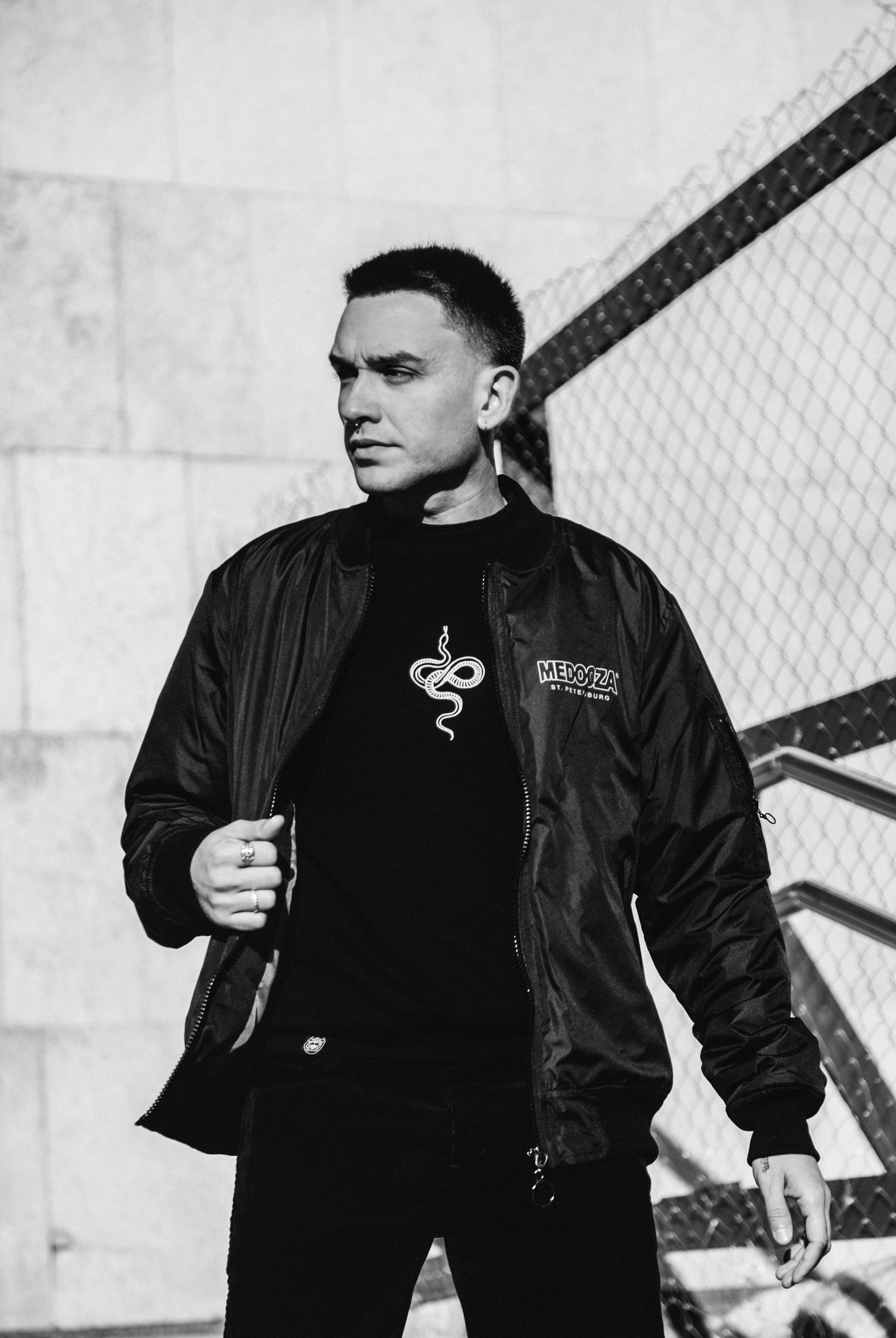 Stylish black and white portrait of a man wearing a jacket, standing outdoors.