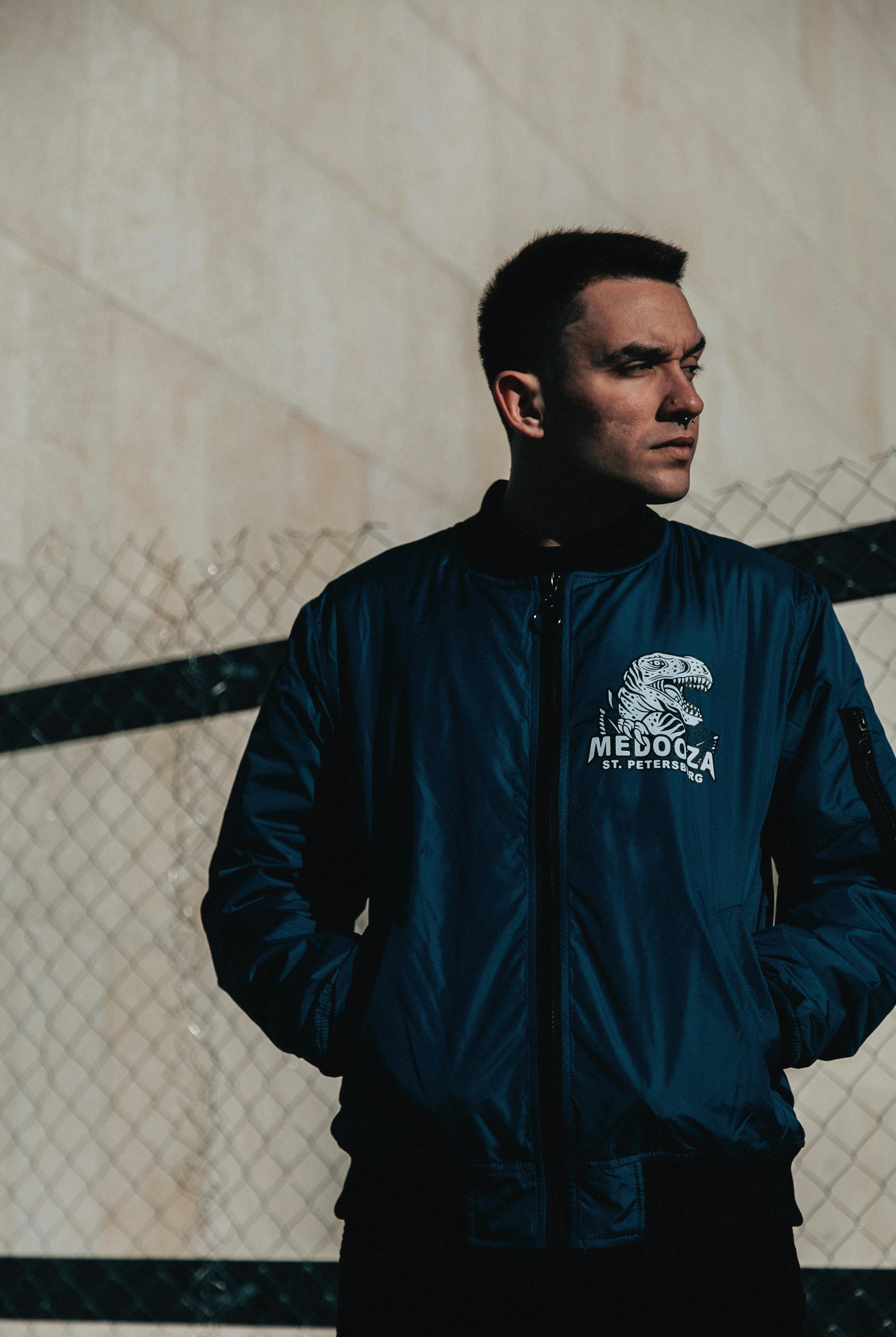 man in black zip up jacket standing near white wall