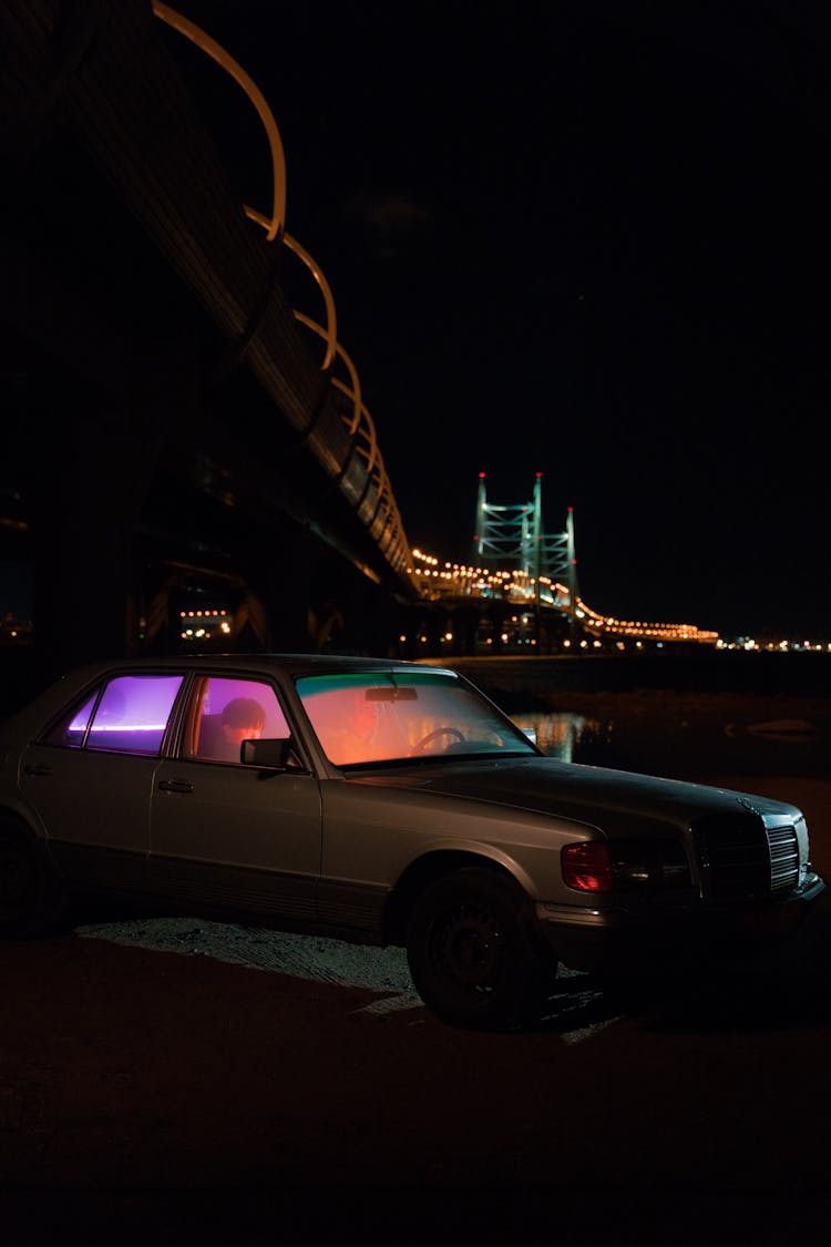 Person Sitting In The Car Under The Bridge At Night