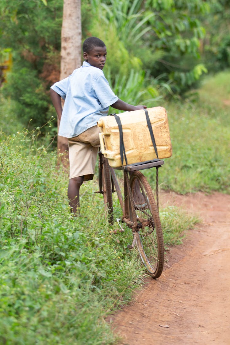 A Boy Riding A Bicycle With A Fuel Container
