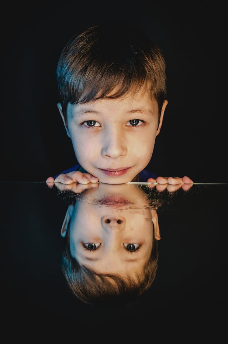 A Boy With Reflection On Glass Table