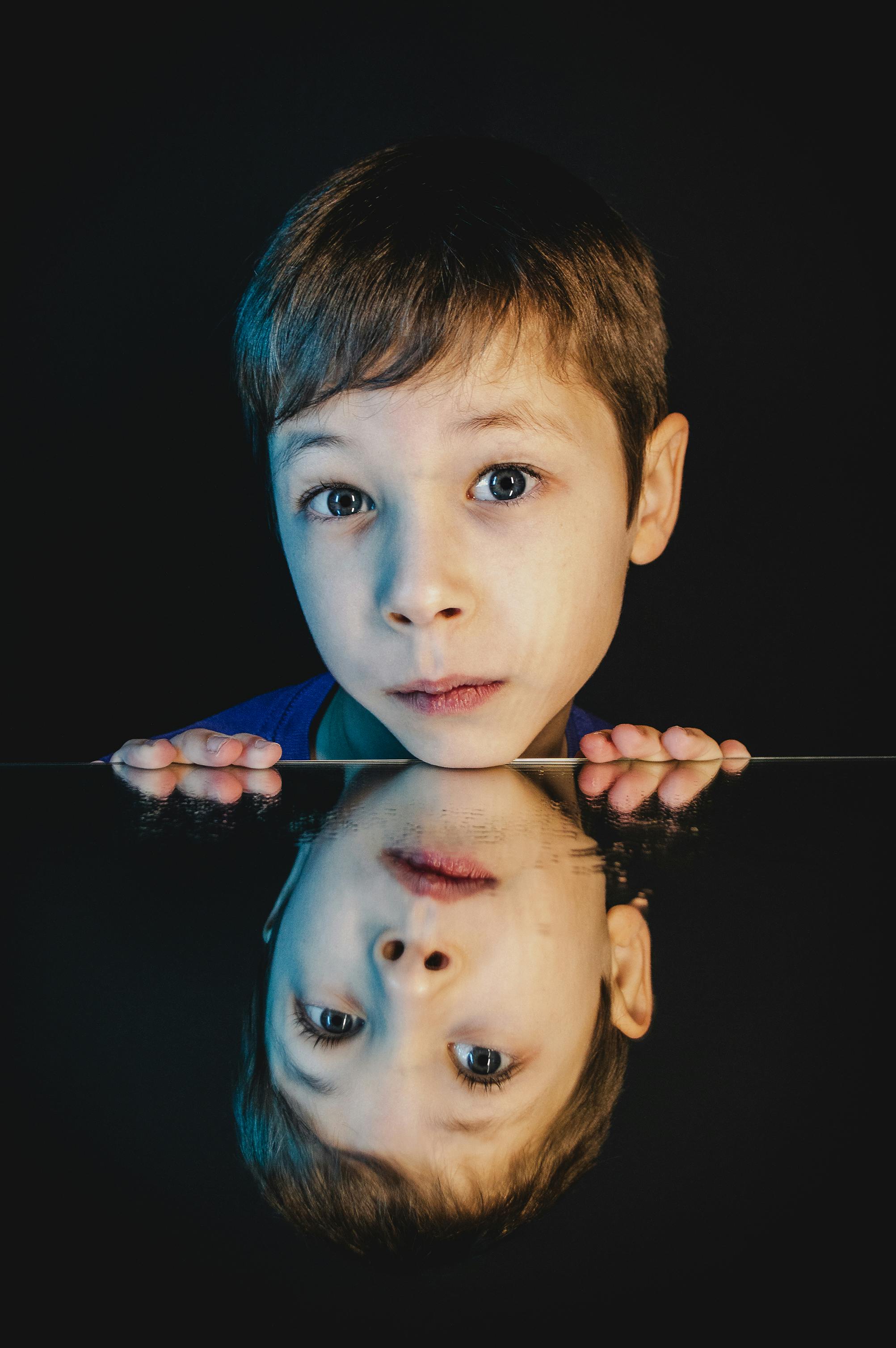 boy s chin leaning on a mirror surface