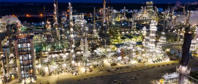 An expansive oil refinery complex brilliantly illuminated at night.