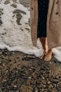 Unrecognizable Woman Standing Dressed and Barefoot on Beach at Seashore