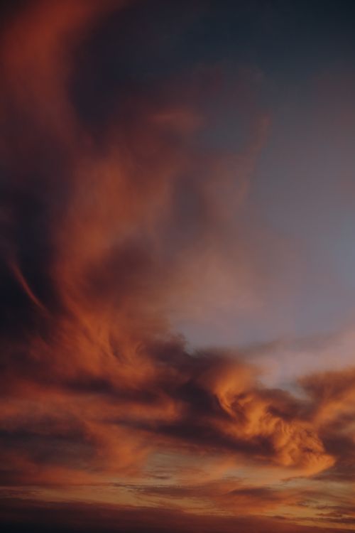 Free A breathtaking view of dramatic clouds at sunset, casting a warm glow in the sky. Stock Photo