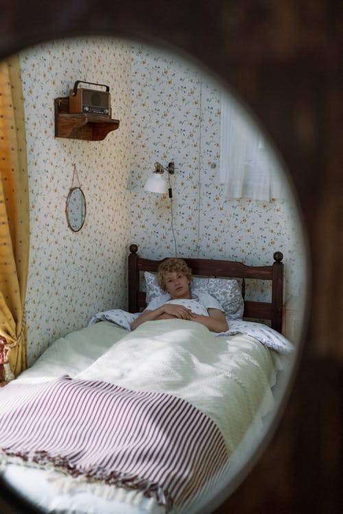 Free Blond Teenage Boy Lying in Bed in Mirror Stock Photo