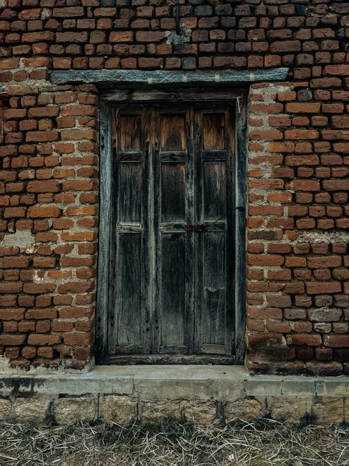 Free A rustic wooden door set in an old brick wall, showcasing traditional architecture in Mandya, India. Stock Photo