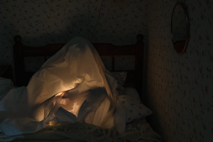 Boy Sitting Under Sheets At Night