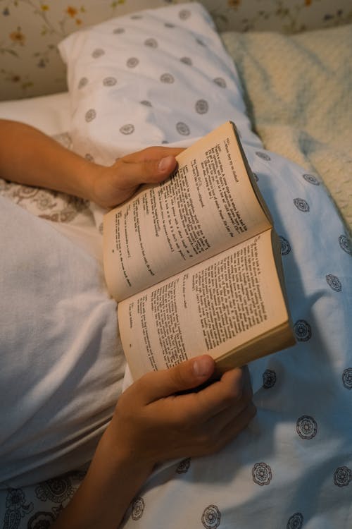 Free Boy Reading Book in Bed Stock Photo