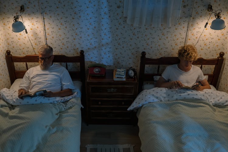 Grandfather And Grandson Lying And Reading In Beds