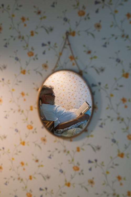 Free Elderly Man in Bed Reading Book in Mirror Stock Photo