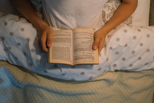 Free Boy Reading Book in Bed Stock Photo