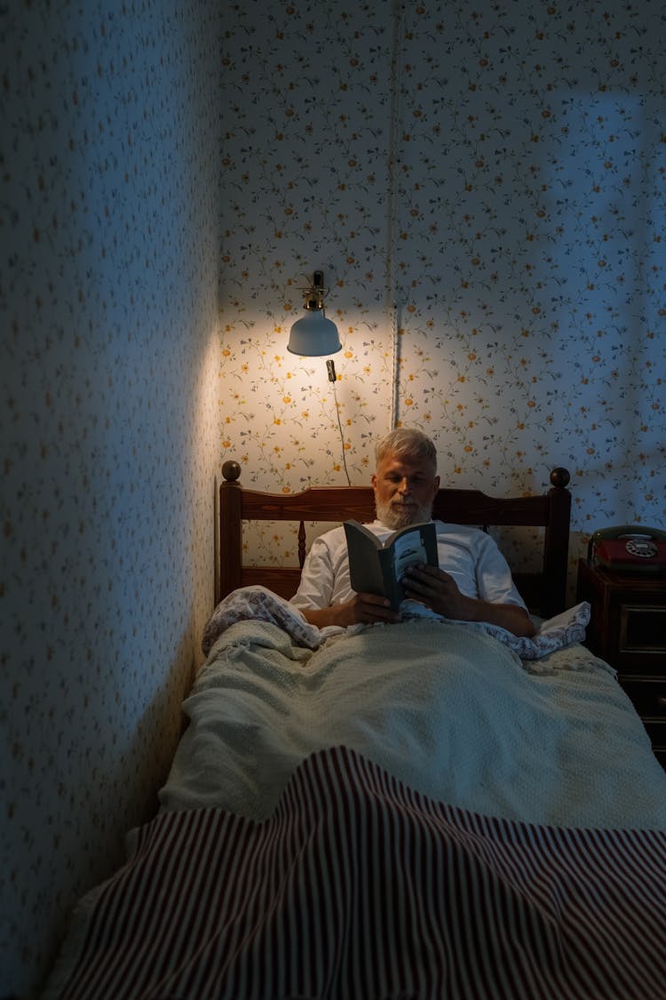 Elderly Man In Bed Reading Book