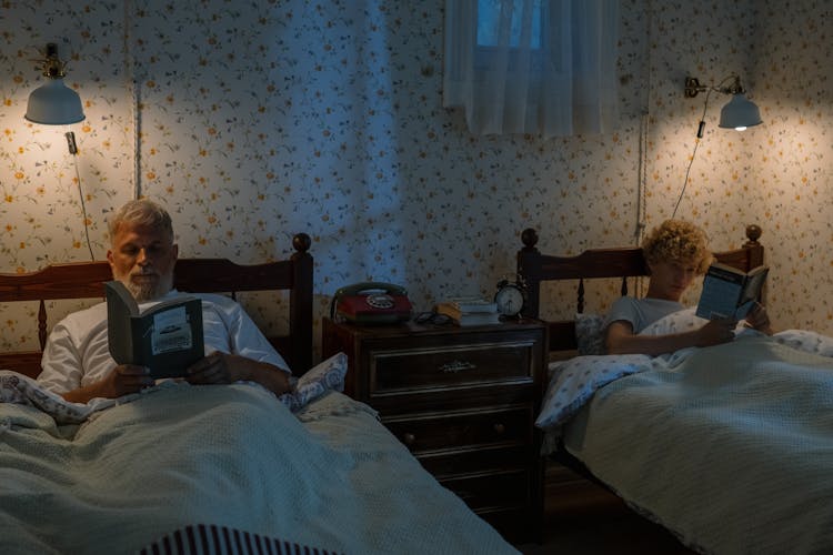 Grandfather And Grandson Lying And Reading In Beds