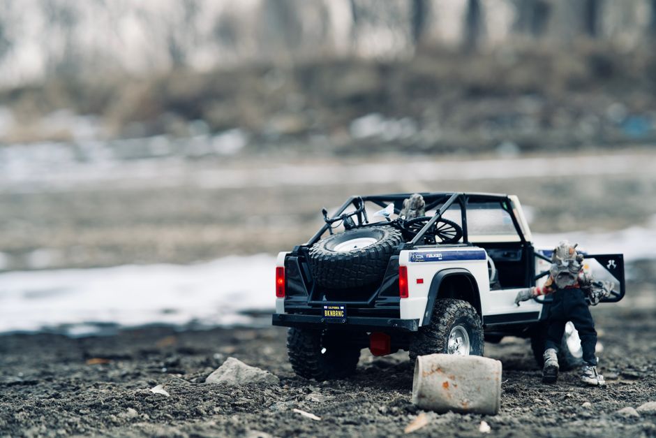 Close-up of a toy truck with figurines on a muddy outdoor landscape, depicting an adventurous scene.