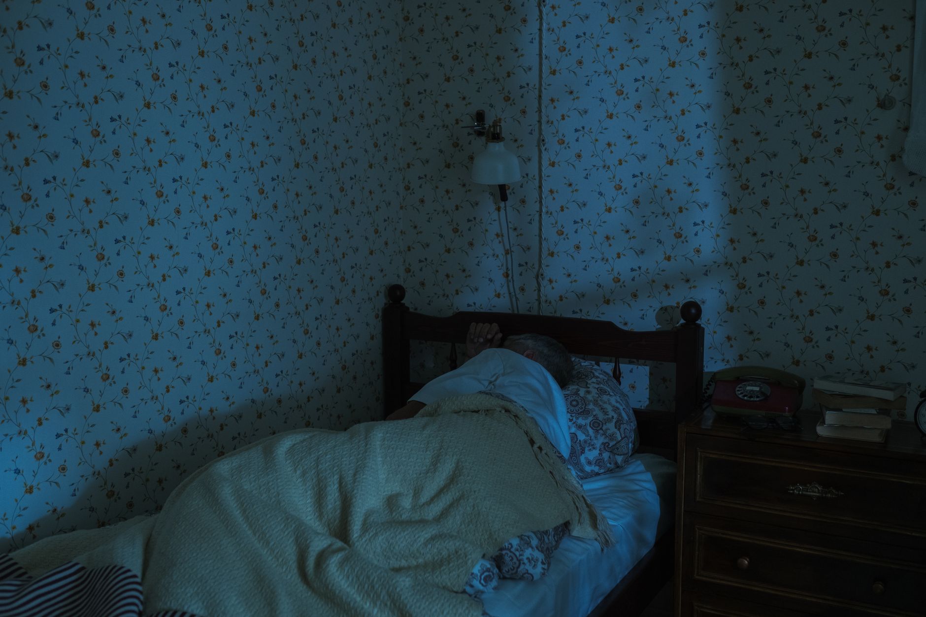 A serene scene of a senior man sleeping peacefully in a vintage-themed bedroom at night.