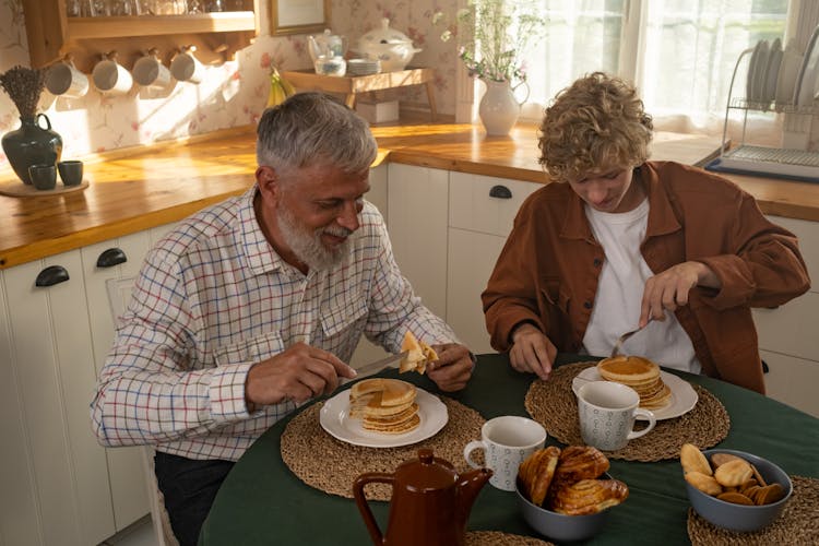 Grandfather And Grandson Eating Pancakes For Breakfast