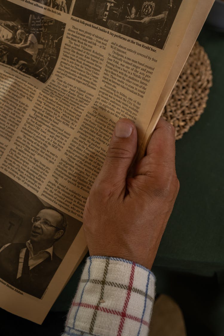 Close-up View Of Hand Holding Newspaper