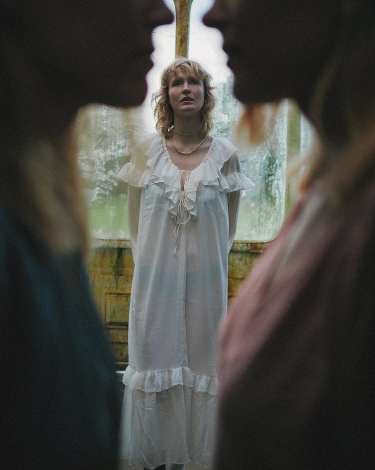 Woman In Long Dress Standing In Between Silhouettes Of Women In Foreground